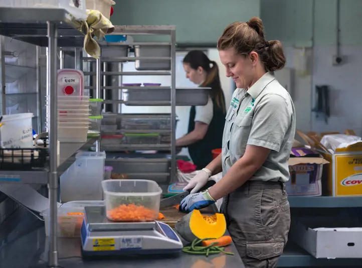 Taronga keeper and volunteer in the kitchen working on preparing food