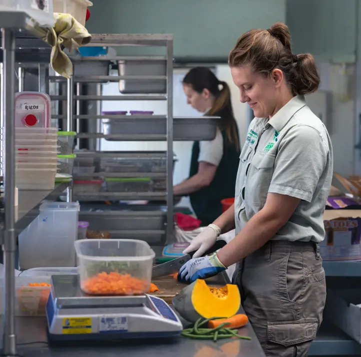Taronga keeper and volunteer in the kitchen working on preparing food