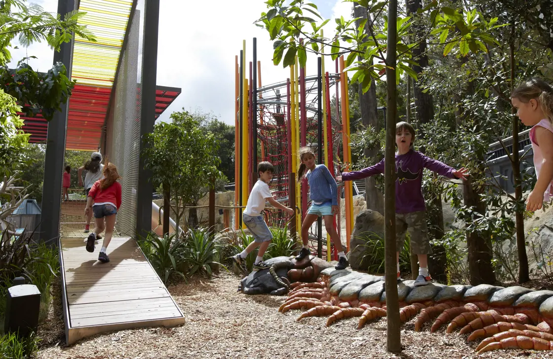 Children playing on a nature-based playground at Taronga Zoo during a vacation care program.