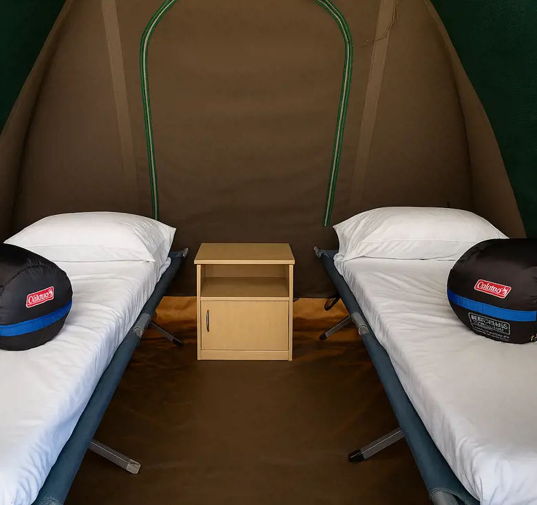 Interior of a safari‑style tent with sleeping bags on two single beds.